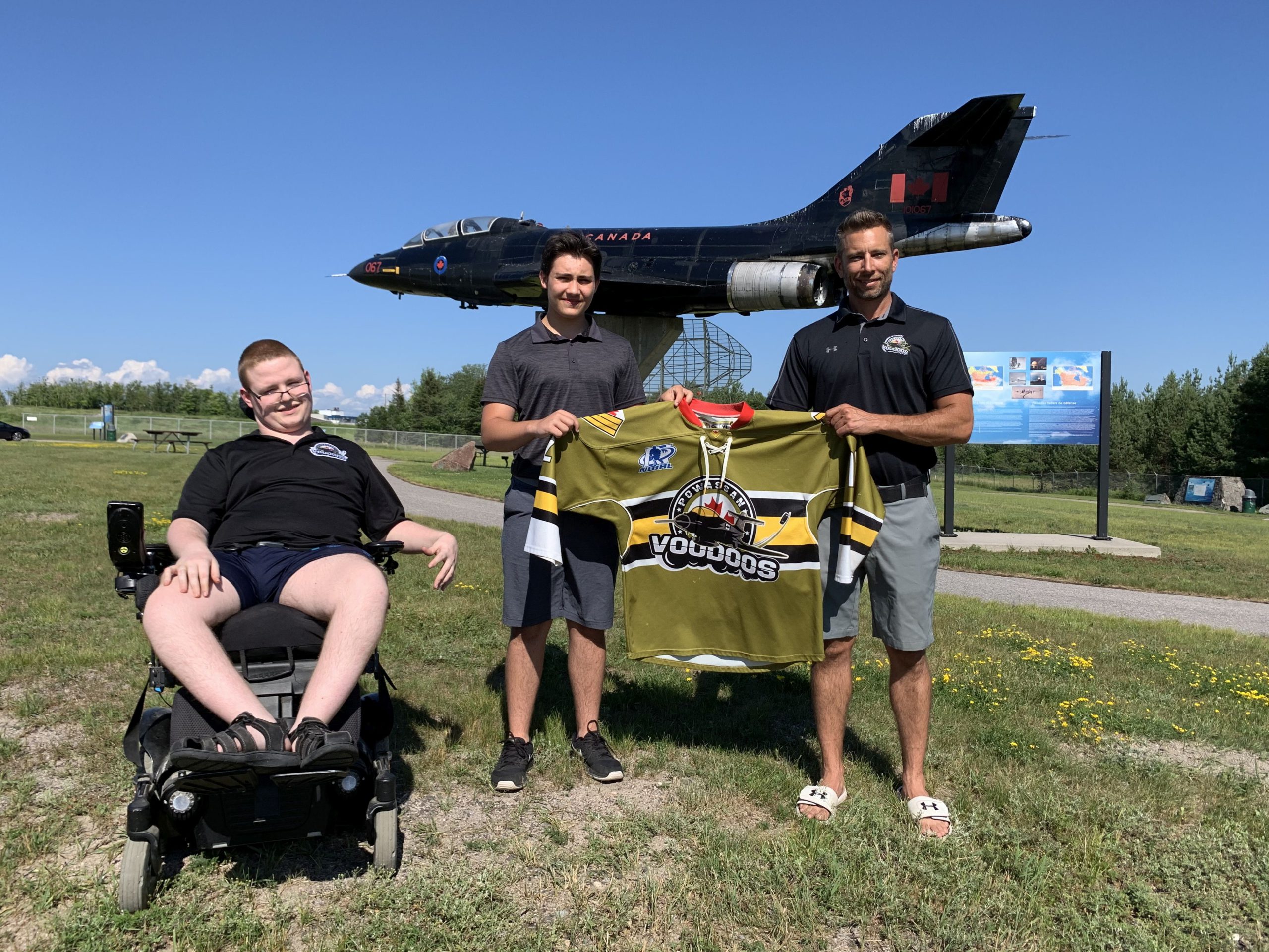 Voodoos northern scout Dillon Anderson (far left), new Voodoos recruit Ben White (middle) and Voodoos assistant coach Josh Dale (right) stand in front of a CF-101 Voodoos Jet at CFB North Bay.