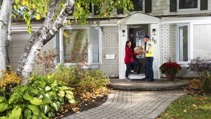 Delivery agent handing a package to a woman outside her home